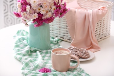 Photo of Cup of fresh coffee and beautiful bouquet on white table
