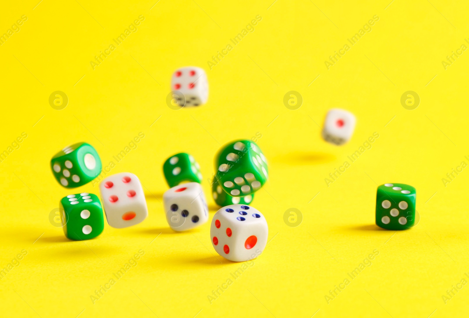 Photo of Many color game dices falling on yellow background