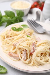 Photo of Plate of tasty pasta Carbonara with basil leaves on table, closeup