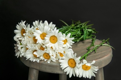 Beautiful chamomile flowers on table against dark background