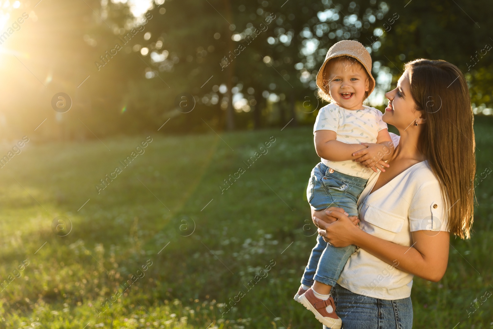 Photo of Happy mother with her cute baby daughter in park on sunny day. Space for text