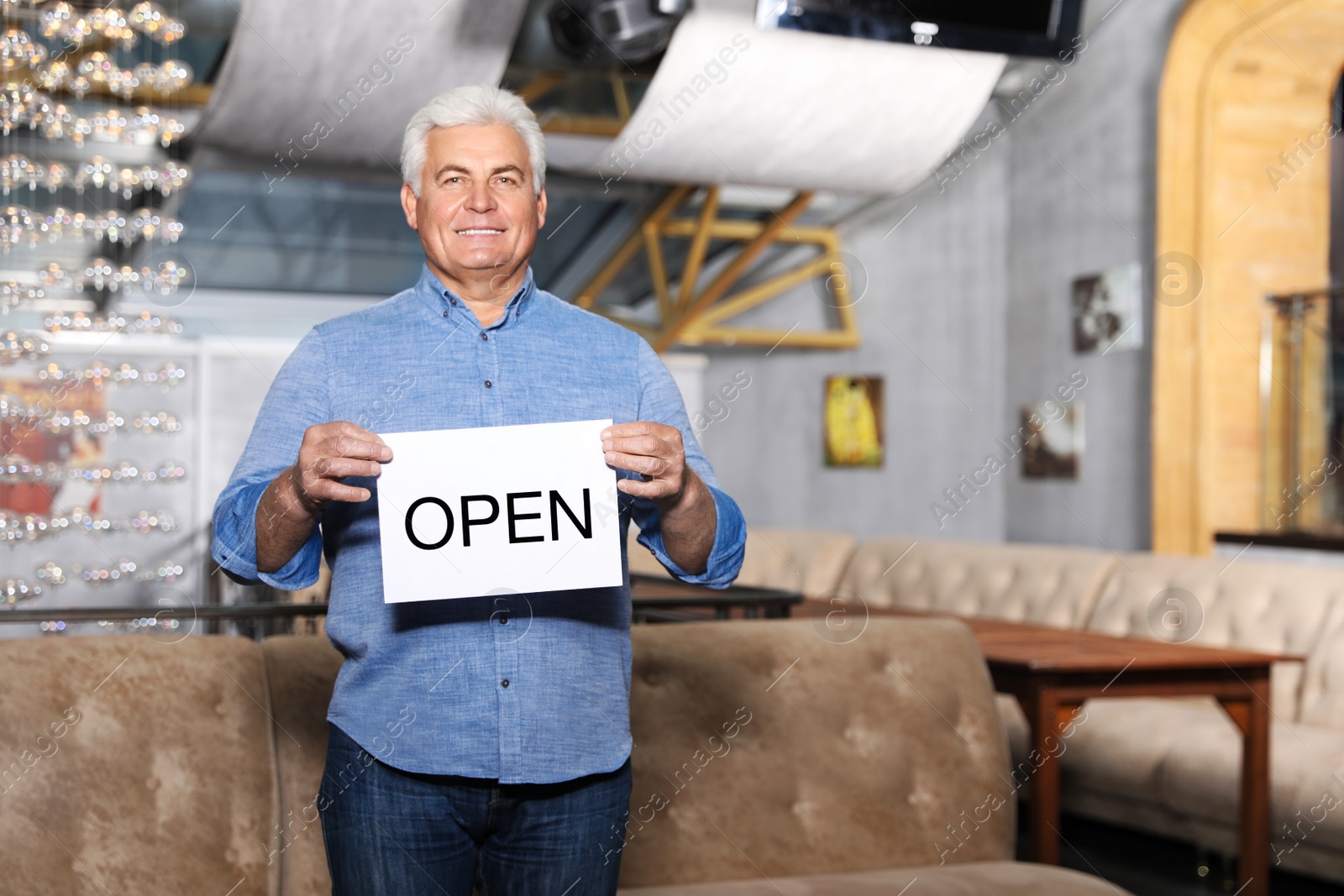 Photo of Senior business owner holding OPEN sign in his restaurant