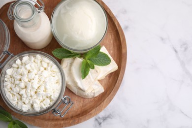 Photo of Different dairy products and mint on white marble table, top view. Space for text