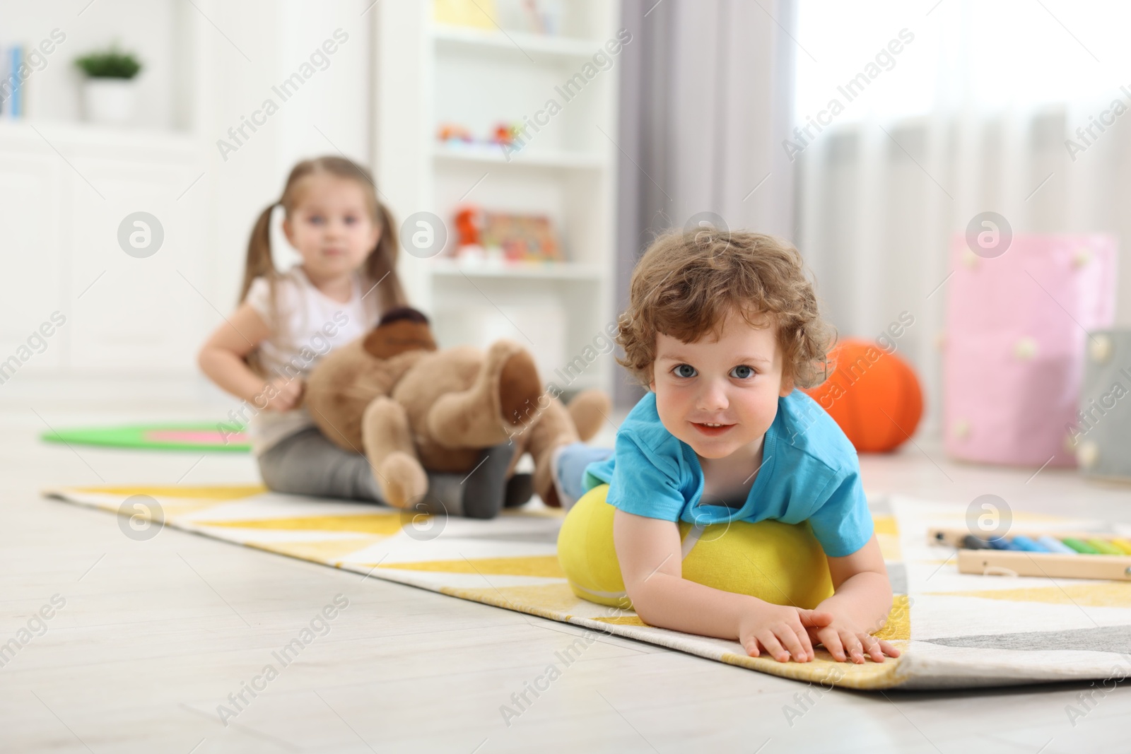 Photo of Cute little children playing together on floor in kindergarten, selective focus