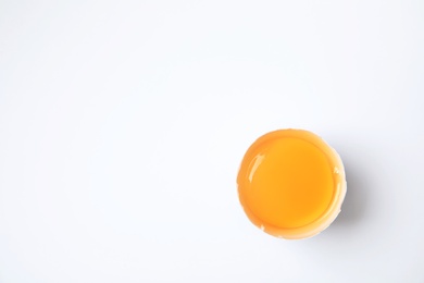 Cracked chicken egg with yolk on white background, top view