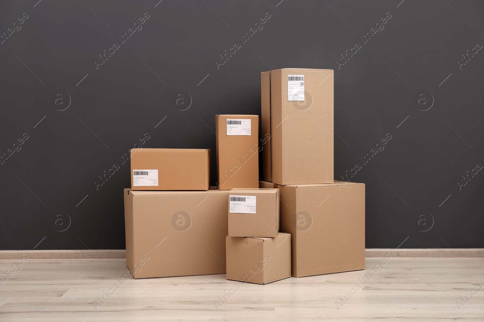 Photo of Stacked parcel boxes on floor against grey wall