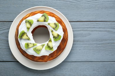 Photo of Homemade yogurt cake with kiwi and cream on grey wooden table, top view. Space for text