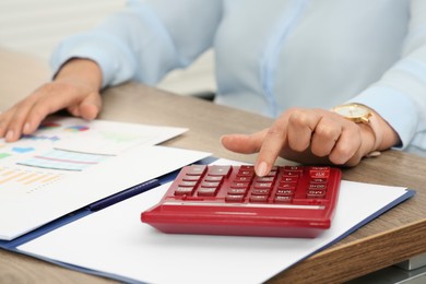Photo of Accountant using calculator at wooden desk in office, closeup