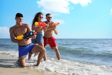 Friends with water guns having fun on beach