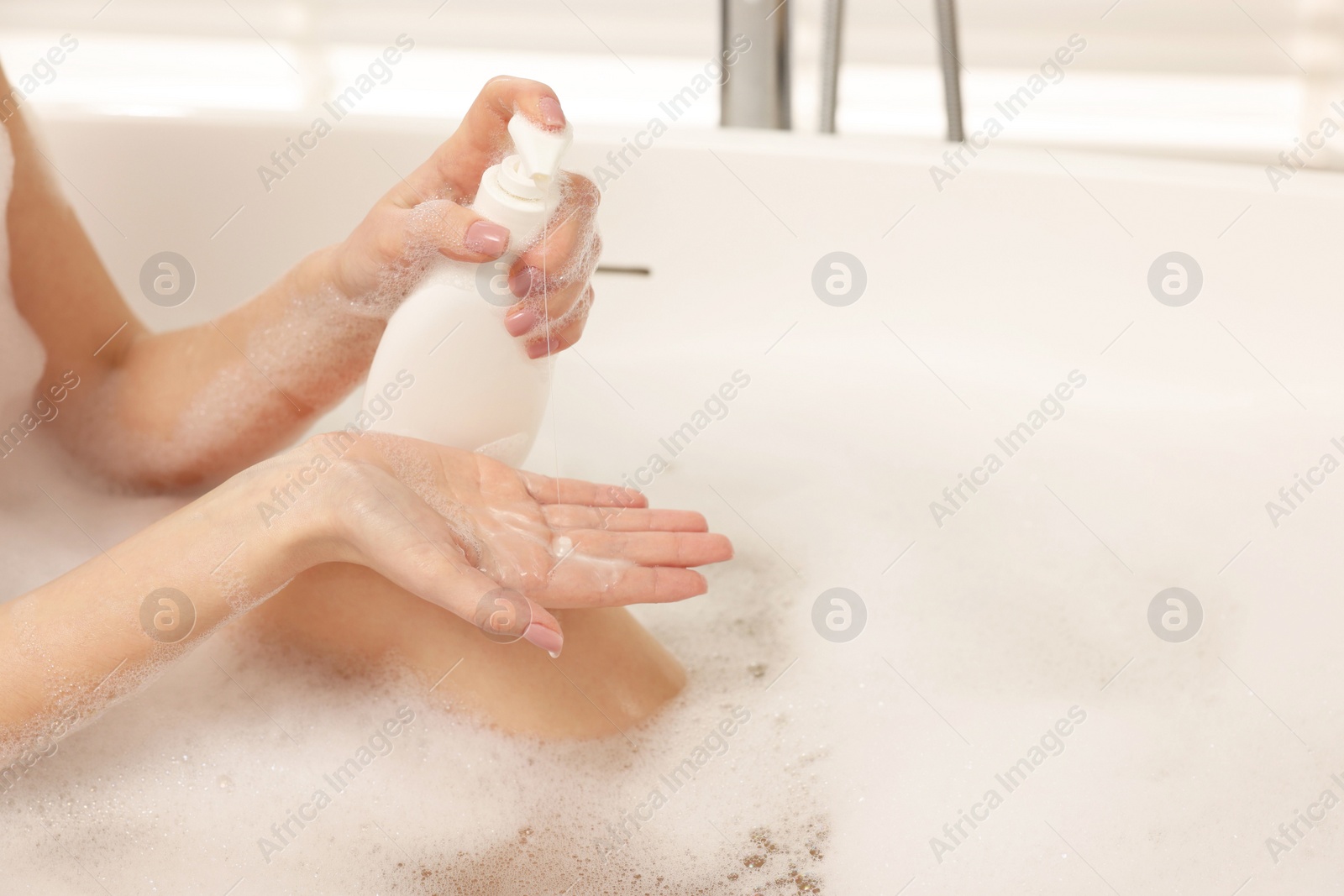 Photo of Woman applying shower gel onto hand in bath indoors, closeup. Space for text