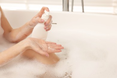 Woman applying shower gel onto hand in bath indoors, closeup. Space for text