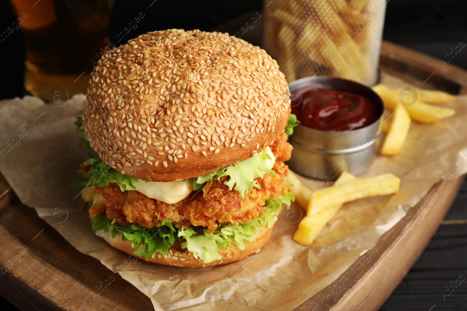 Photo of Delicious burger with crispy chicken patty, french fries and sauce on table, closeup