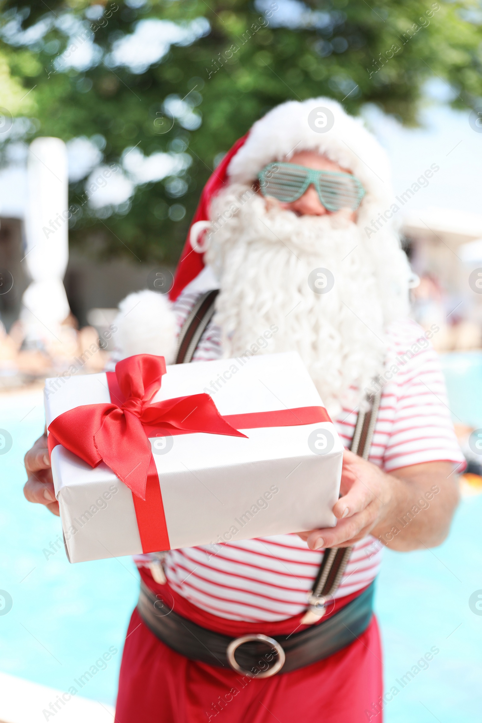 Photo of Authentic Santa Claus with gift near pool at resort