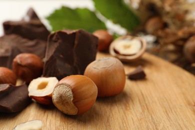 Delicious chocolate chunks and hazelnuts on wooden table, closeup. Space for text