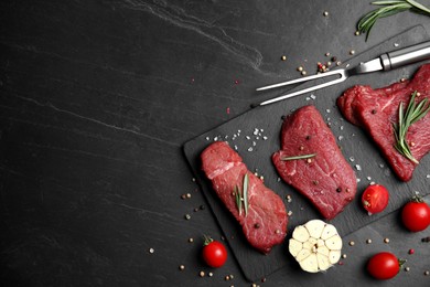 Photo of Fresh raw meat steaks and spices on black table, flat lay. Space for text