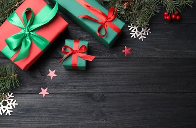 Flat lay composition with gift boxes and Christmas decorations on dark grey wooden table, space for text