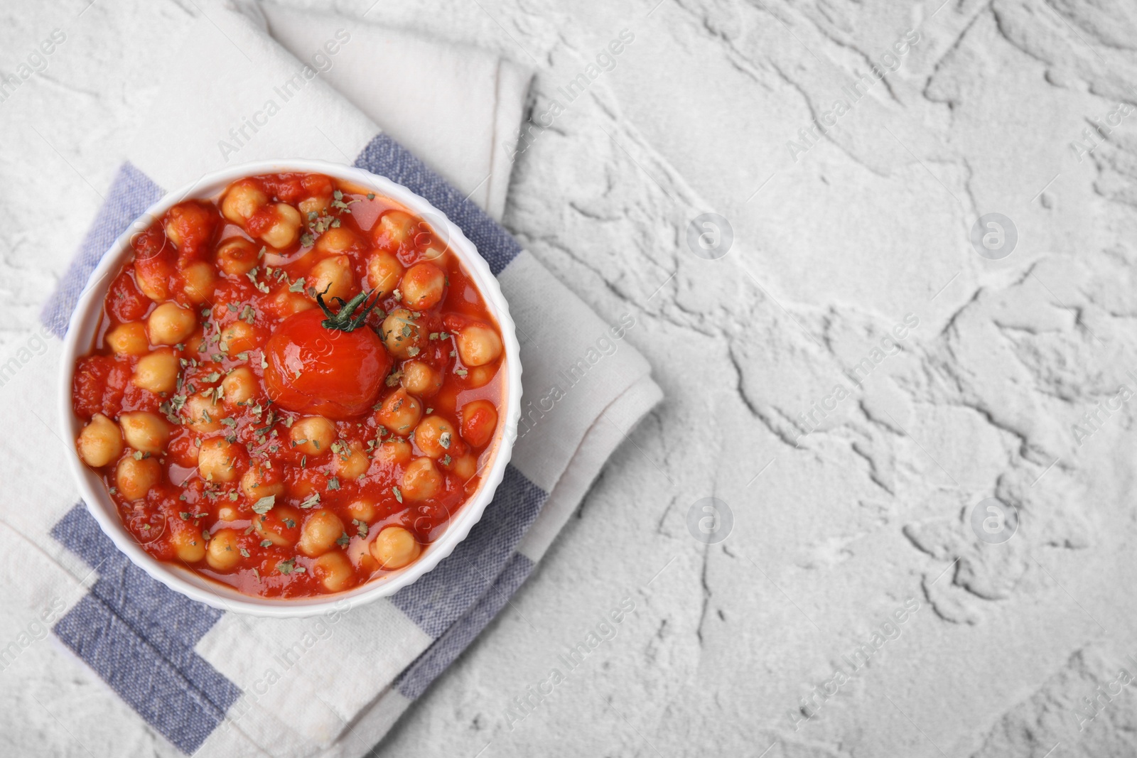 Photo of Delicious chickpea curry in bowl on white textured background, top view. Space for text