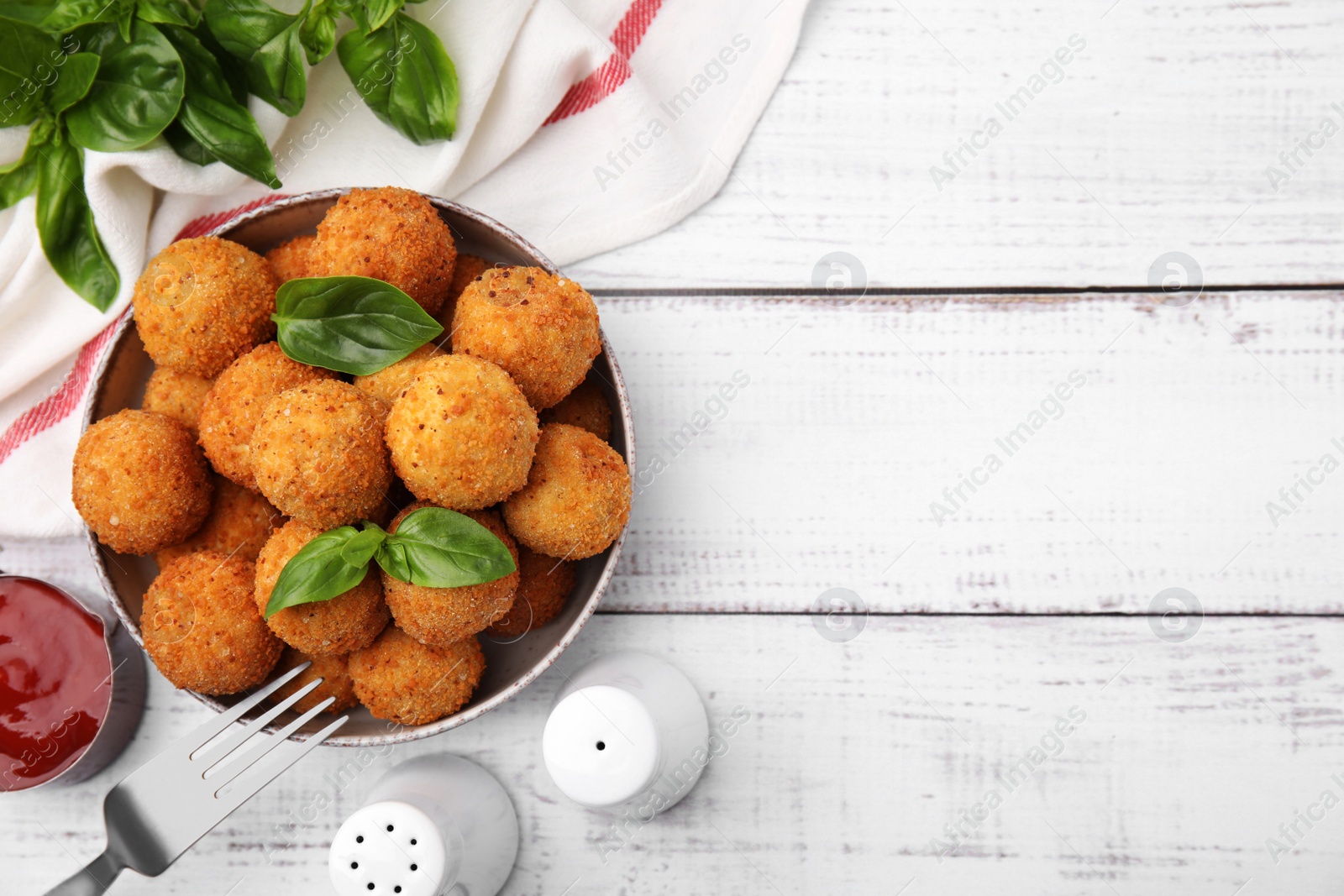 Photo of Bowl of delicious fried tofu balls with basil on white wooden table, flat lay. Space for text