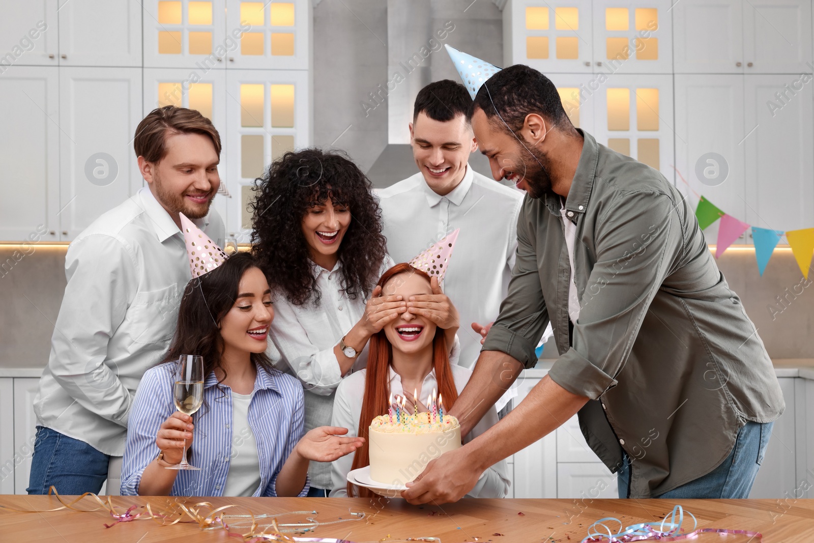 Photo of Happy friends with tasty cake celebrating birthday in kitchen