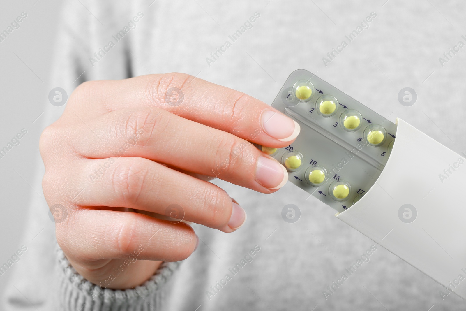 Photo of Woman holding blister with birth control pills, closeup