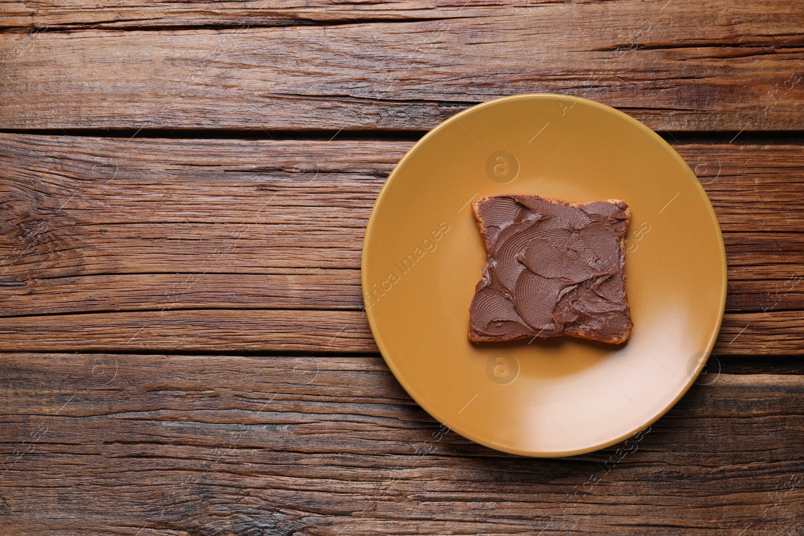 Photo of Toast with tasty nut butter on wooden table, top view. Space for text