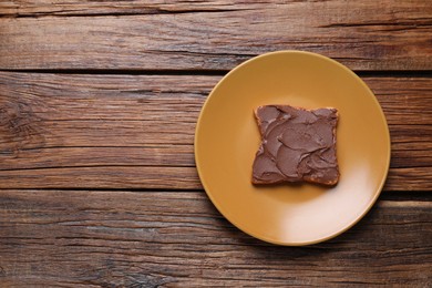 Toast with tasty nut butter on wooden table, top view. Space for text