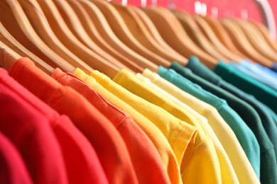 Photo of Hangers with bright clothes as background, closeup