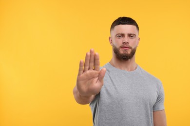 Photo of Man showing stop gesture on orange background, space for text