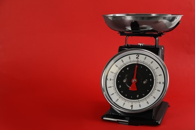 Photo of Retro mechanical kitchen scale on red background, space for text