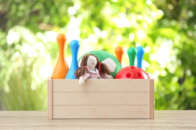 Box with different child toys on table against blurred background