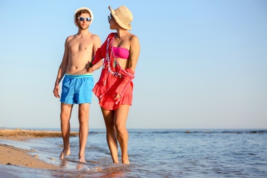 Photo of Happy young couple walking together on beach. Space for text