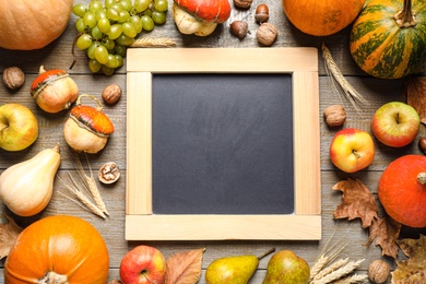 Photo of Chalkboard with space for text, autumn fruits and vegetables on wooden background, flat lay. Happy Thanksgiving day