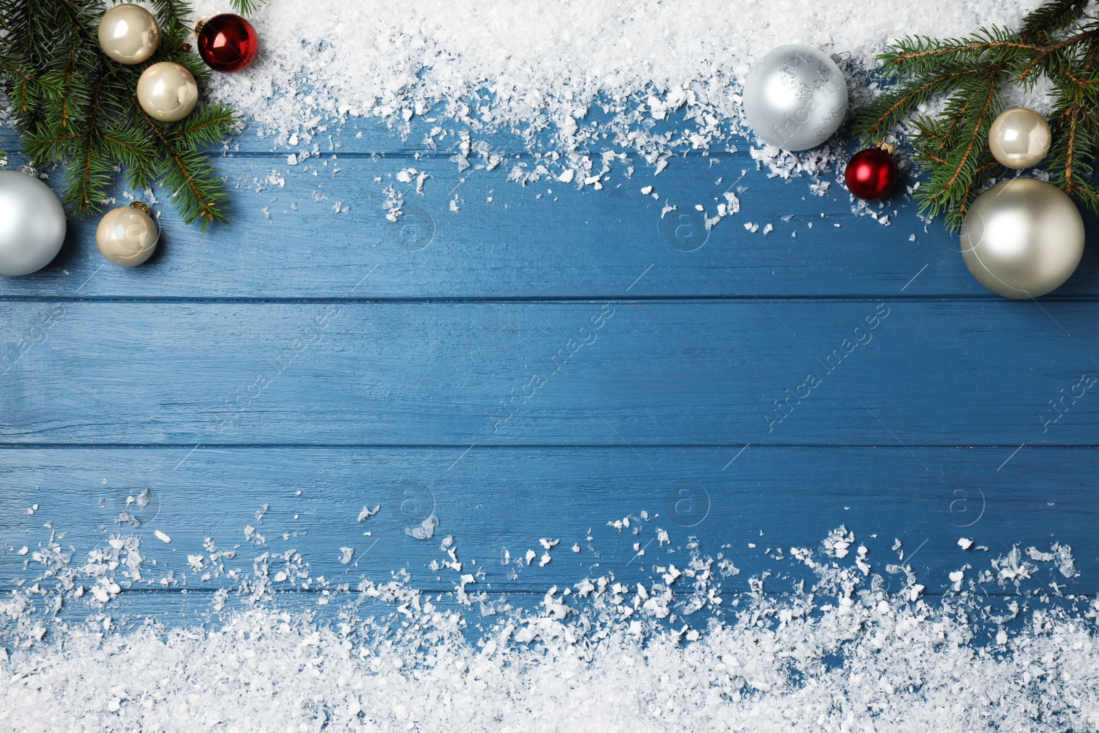 Photo of Christmas decoration with white snow on blue wooden background, flat lay. Space for text