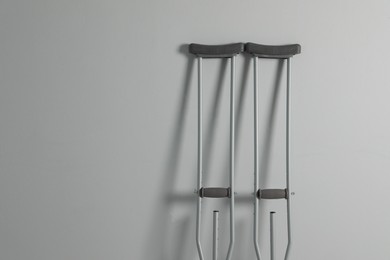 Pair of axillary crutches on light grey background. Space for text