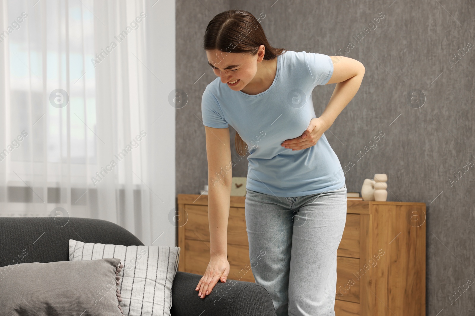 Photo of Woman having heart attack near sofa at home