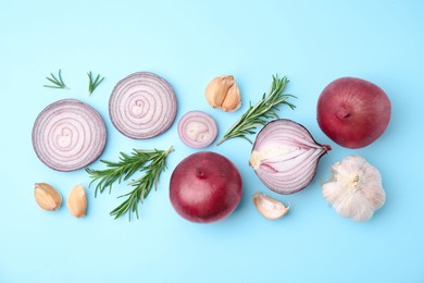 Photo of Fresh red onions, garlic and rosemary on light blue background, flat lay