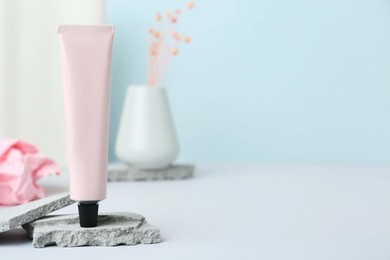 Photo of Tube of hand cream on light gray table, space for text