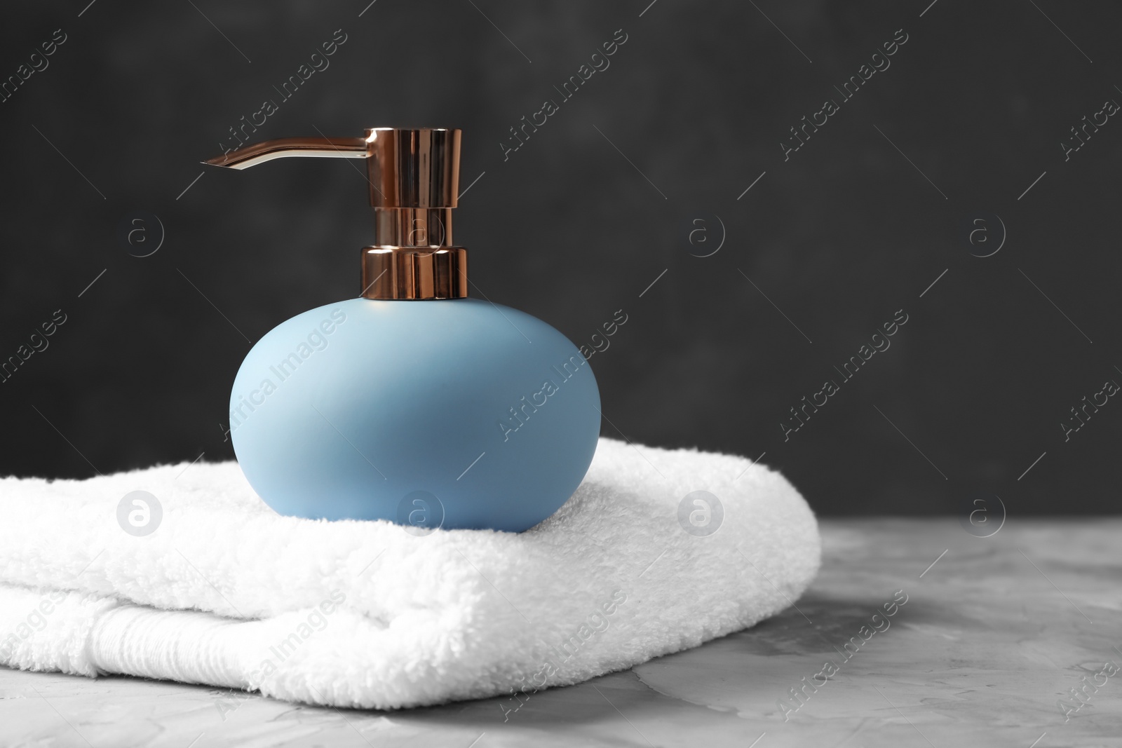 Photo of New stylish soap dispenser and towel on table. Space for text