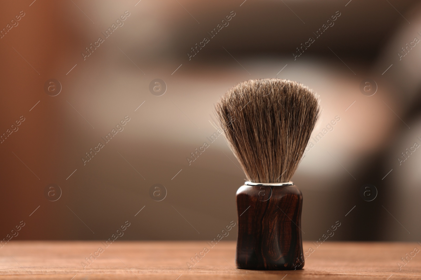 Photo of Shaving brush on table against blurred background with space for text