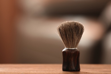 Photo of Shaving brush on table against blurred background with space for text