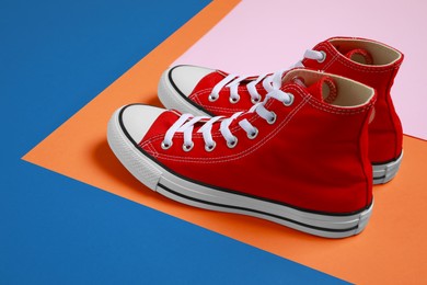 Pair of new stylish red sneakers on colorful background