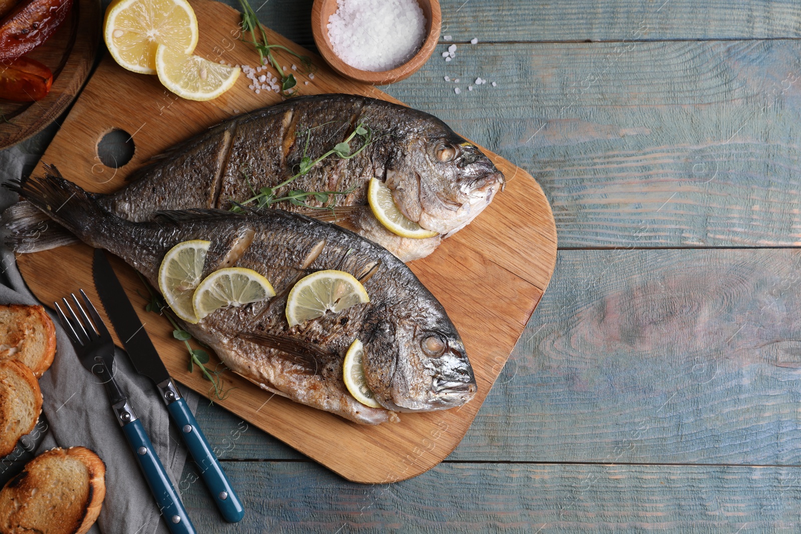 Photo of Delicious baked fish served on wooden rustic table, flat lay with space for text. Seafood