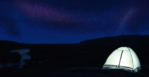 Modern camping tent glowing in twilight outdoors. Banner design