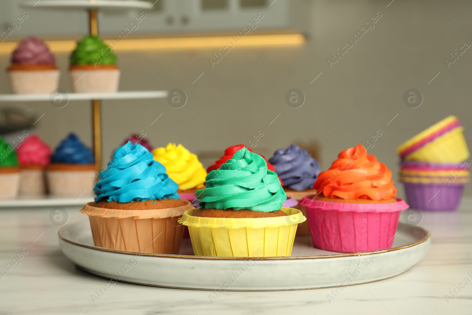 Photo of Delicious cupcakes with colorful cream on white table