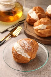 Delicious profiteroles filled with cream on grey table, space for text
