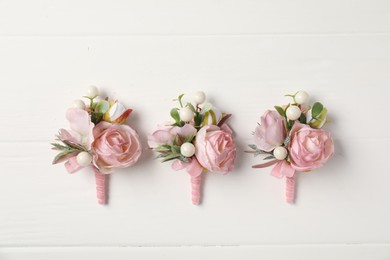 Photo of Beautiful boutonnieres on white background, flat lay