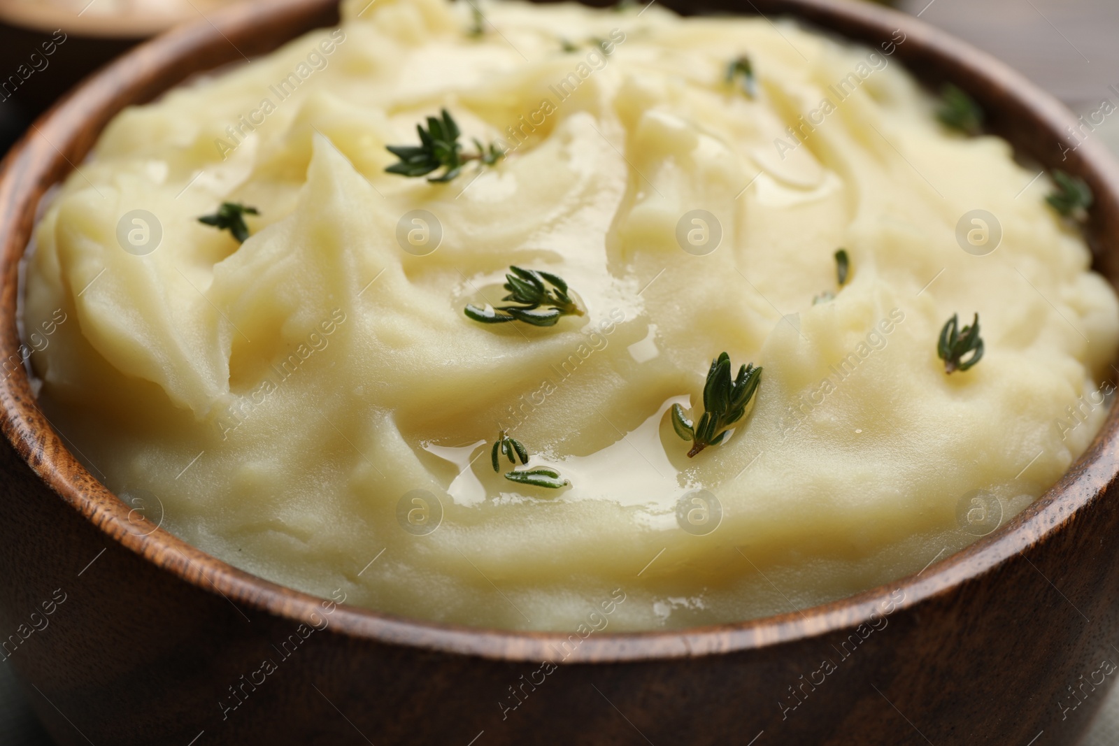 Photo of Bowl of delicious mashed potato with thyme, closeup