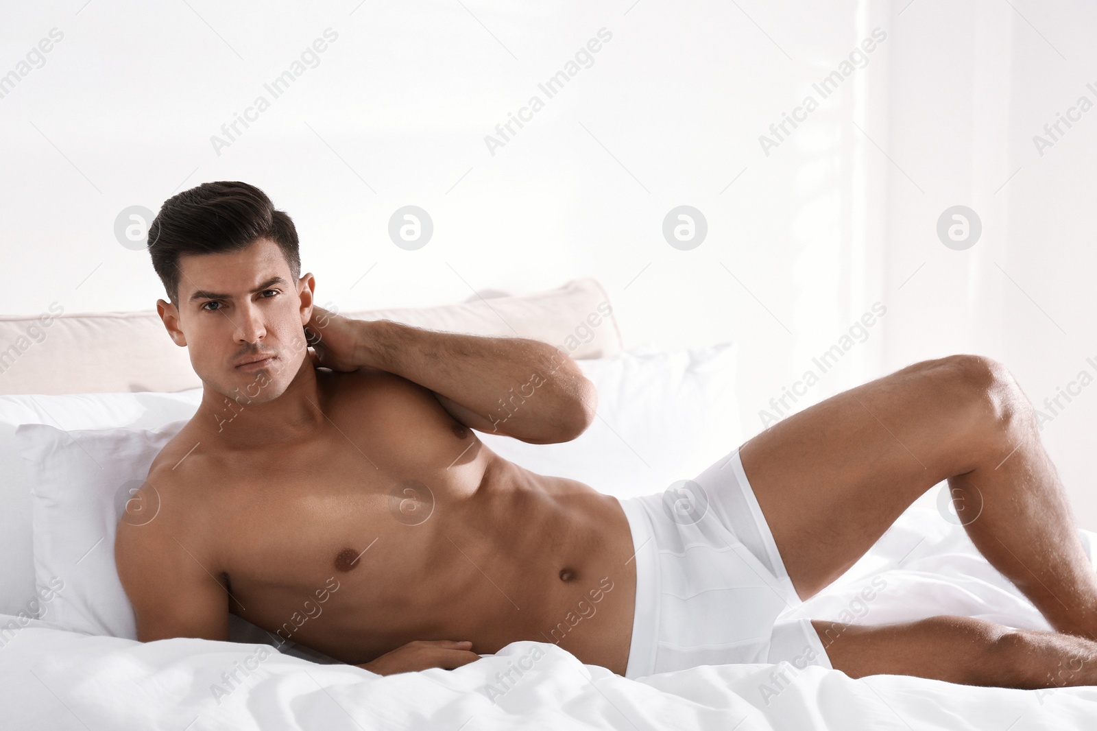 Photo of Handsome man in white underwear on bed indoors