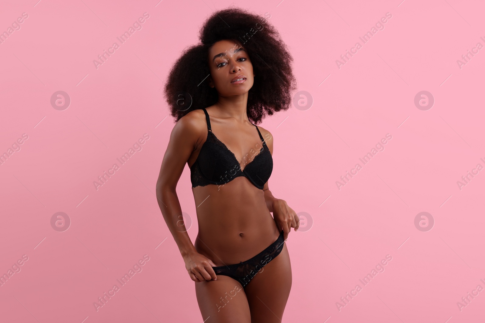 Photo of Beautiful woman in elegant black underwear on pink background