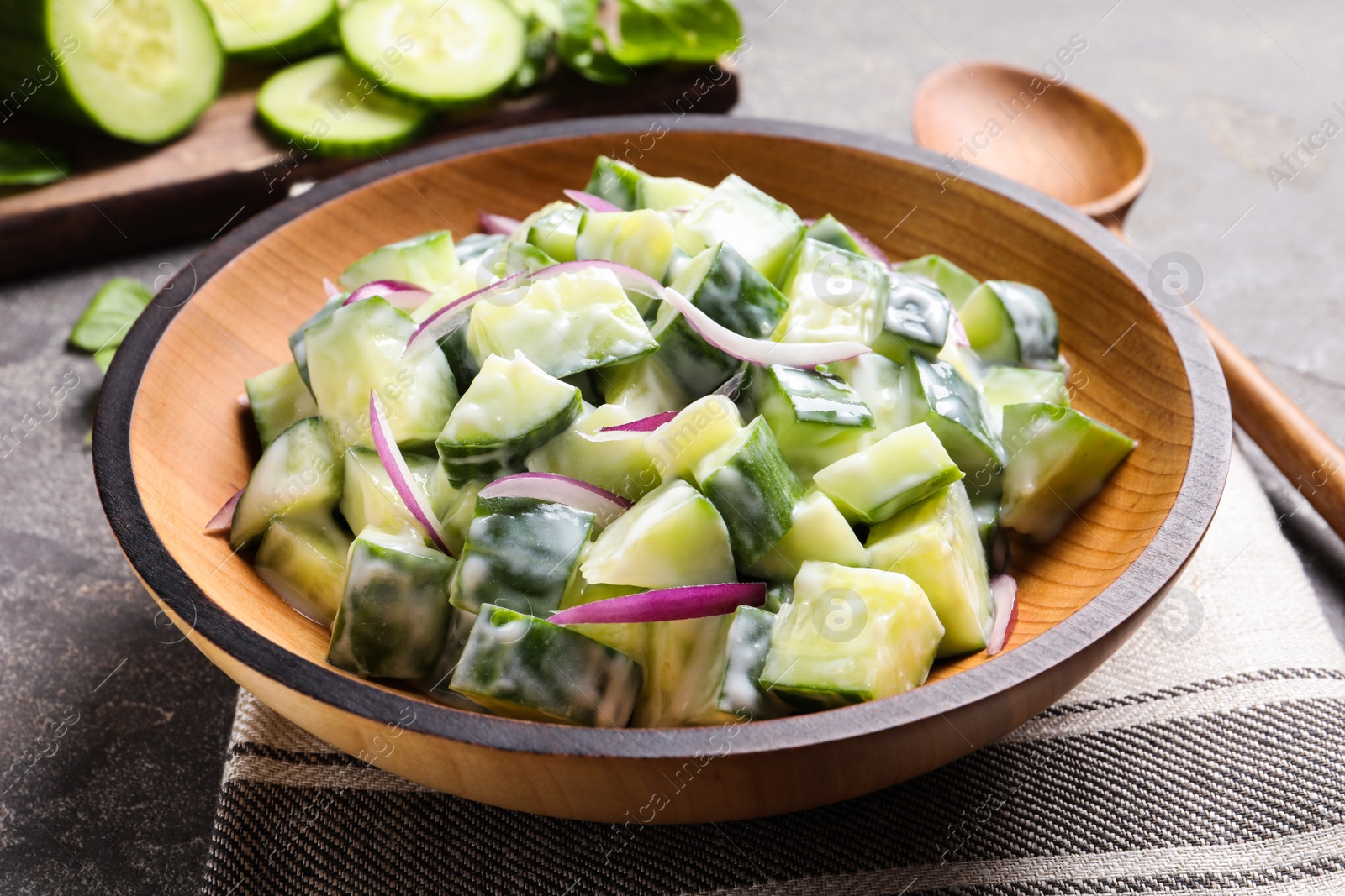 Photo of Wooden dish with fresh creamy cucumber salad served on table